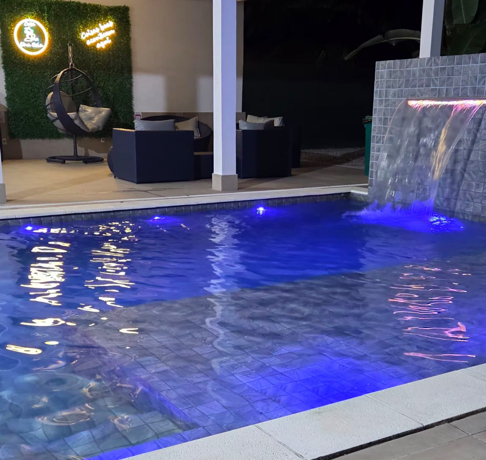 Piscina com cascata iluminada à noite